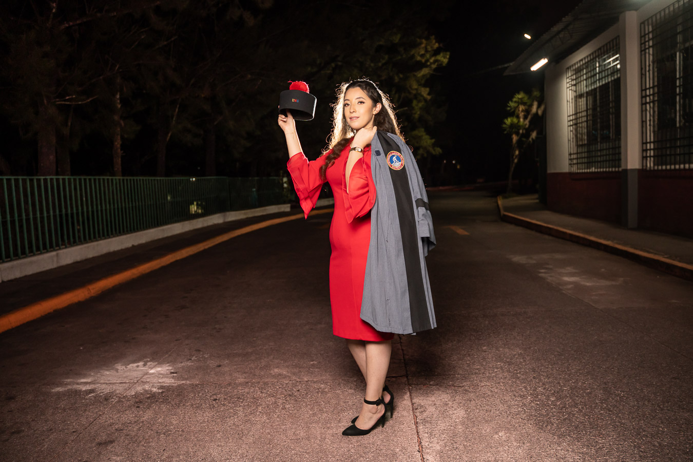 Graduada con birrete en mano y toga en el hombro