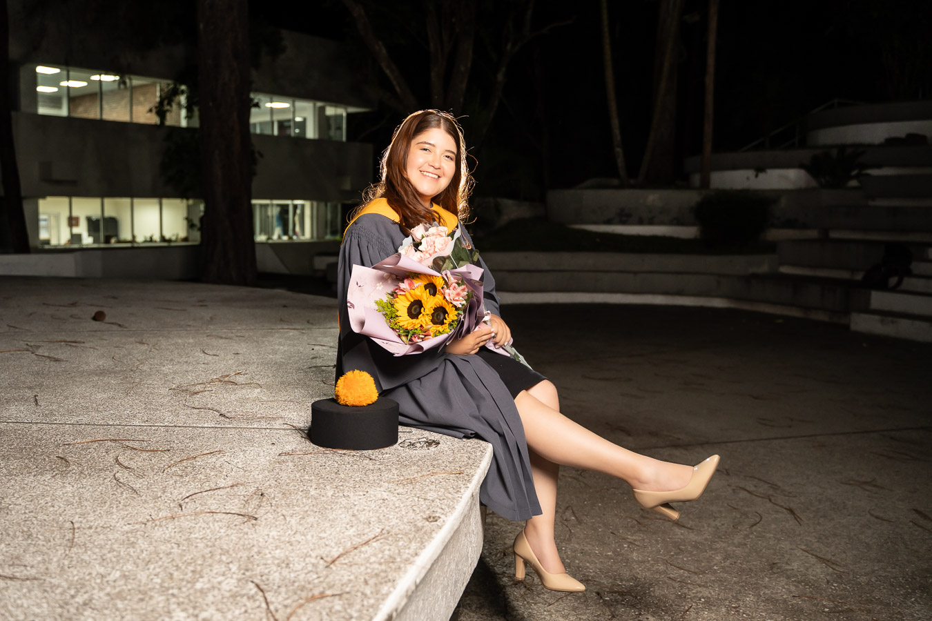 Graduada sentada con arreglo de flores
